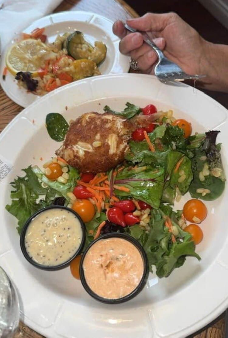 A crab cake on a salad with two dipping sauces